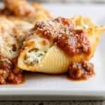 Close-up of a stuffed pasta shell topped with marinara sauce and sprinkled with Parmesan cheese.