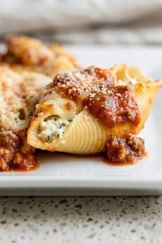 Cottage Cheese Jumbo Stuffed Shells Pasta Recipe Close-up of a stuffed pasta shell topped with marinara sauce and sprinkled with Parmesan cheese.