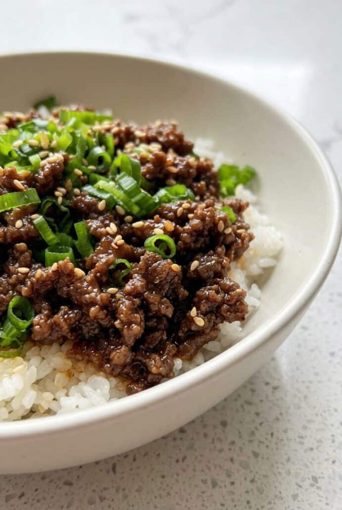 Close-up of Korean beef bowl with ground beef and green onions over rice, featured in this quick and easy dinner recipe.