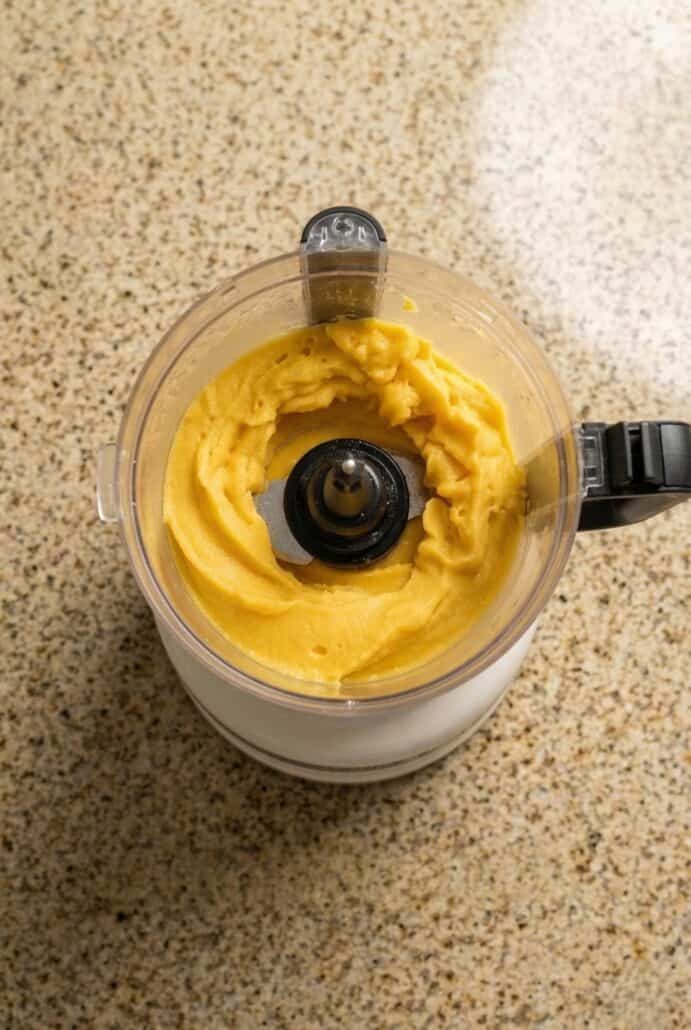 Mango sorbet being blended in a food processor, showing the smooth puree step before churning in this easy homemade mango sorbet recipe.