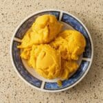 Mango sorbet scoops served in a bowl, showcasing the smooth texture and vibrant color.