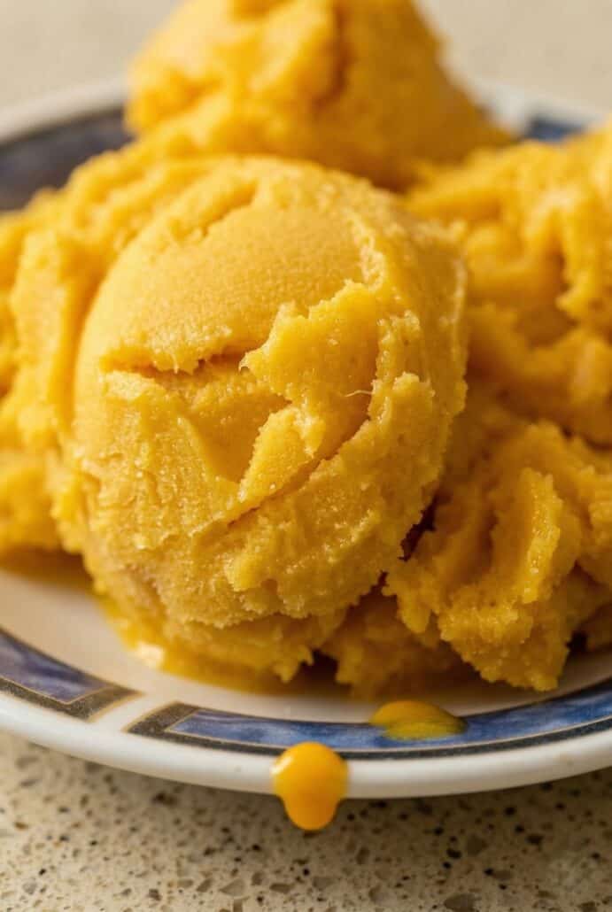 Close-up of a smooth mango sorbet scoop, highlighting the creamy texture and rich color.