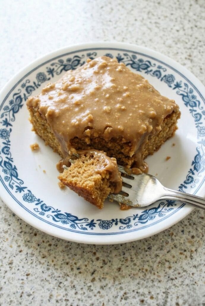 Slice of peanut butter sheet cake with a bite taken out and creamy peanut butter frosting on top, showcasing the soft crumb and rich texture of this easy homemade dessert.