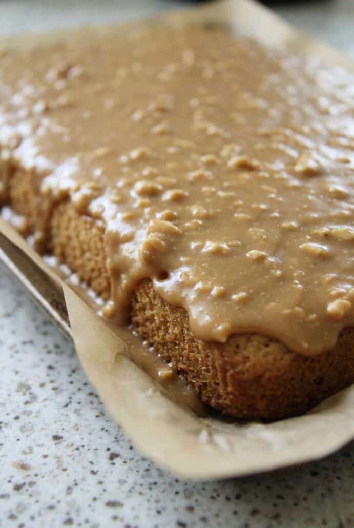 Close-up of moist peanut butter sheet cake with warm peanut butter frosting poured over the top, showing the soft texture inside this easy homemade dessert.