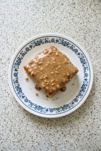 Peanut Butter Sheet Cake | Easy Crowd-Pleasing Dessert Recipe Square slice of peanut butter sheet cake with creamy peanut butter frosting served on a decorative plate.
