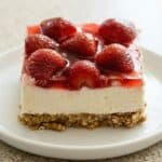 Slice of strawberry pretzel salad with creamy cheesecake layer, fresh strawberry topping, and buttery pretzel crust.