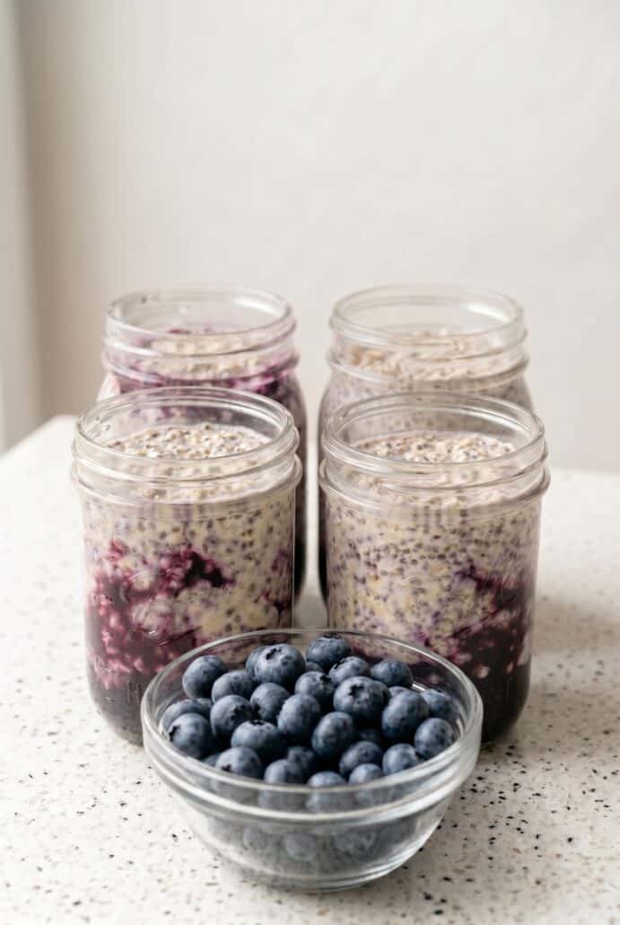 Blueberry overnight oats in glass jars with fresh blueberries, a simple healthy breakfast meal prep recipe.