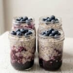 Blueberry overnight oats in mason jars topped with fresh blueberries.