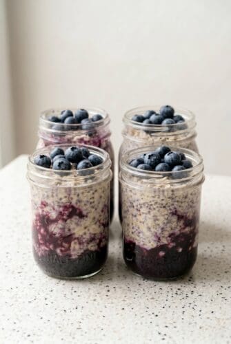 Blueberry overnight oats in mason jars topped with fresh blueberries.