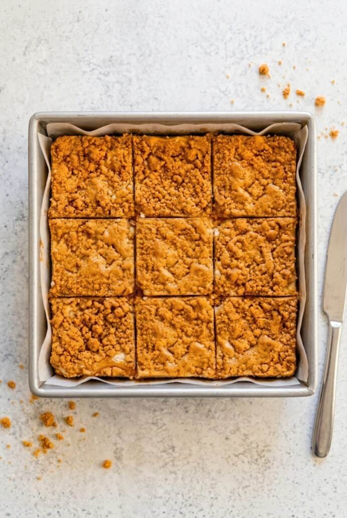 Overhead view of butterscotch graham cracker cheesecake bars baked and sliced in a pan.