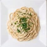 Creamy fettuccine Alfredo plated and topped with fresh parsley.