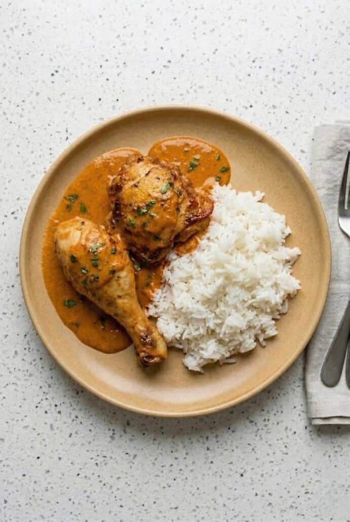 Hungarian chicken paprikash served with rice on a plate, showing creamy paprika sauce.