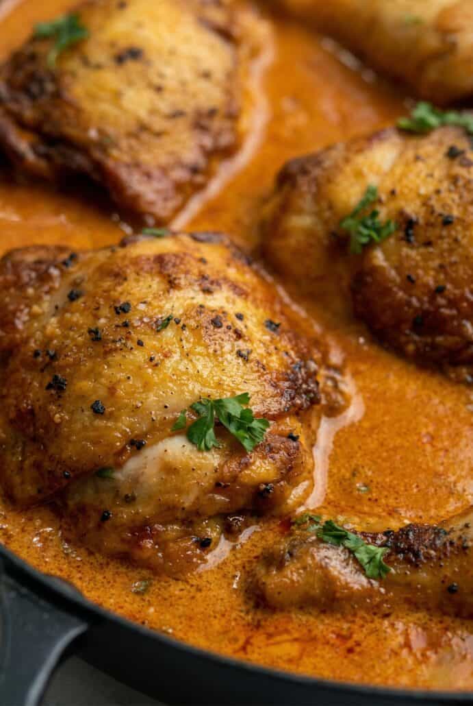 Close-up of tender chicken in creamy paprika sauce, highlighting rich texture.