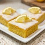 Lemon brownies with glaze and fresh lemon slices on top, served as a bright citrus dessert.