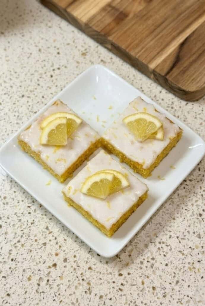 Plated lemon brownies topped with glaze and lemon slices, ready to serve as a fresh and zesty homemade dessert.