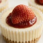Mini cheesecake topped with fresh strawberry and jam, shown as a serving idea for the mini cheesecakes recipe.