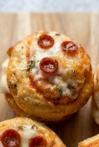 Pizza Cupcakes – Easy, Cheesy & Fun Party Appetizer Recipe Close-up of a single mini pizza cupcake with melted cheese, pepperoni, and a sprinkle of herbs, showing its golden, crispy texture.