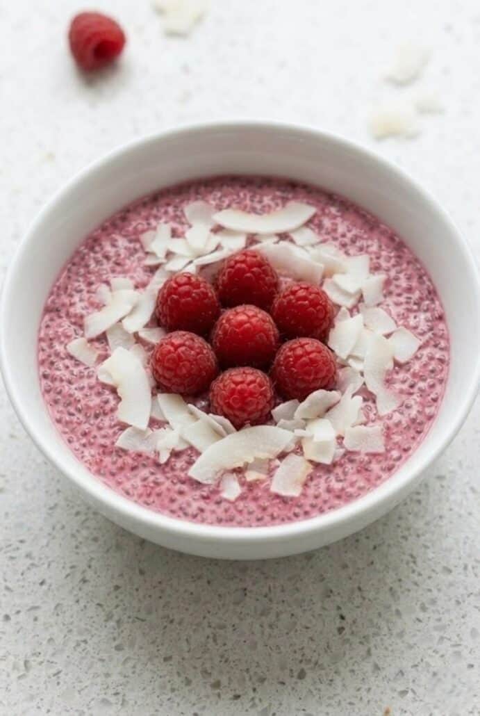 Raspberry chia pudding topped with fresh raspberries and coconut flakes, a healthy vegan breakfast.