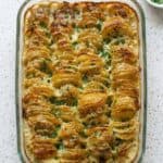 Golden baked scalloped potatoes in a casserole dish with crispy edges and fresh parsley, perfect as a classic creamy side dish.