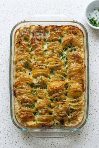 Scalloped Potatoes | Perfect Holiday Side Dish Recipe Golden baked scalloped potatoes in a casserole dish with crispy edges and fresh parsley, perfect as a classic creamy side dish.