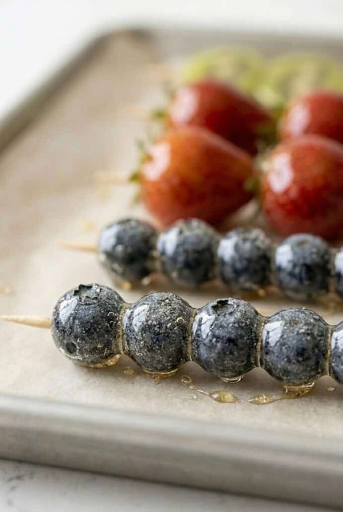 Close-up of sugar-coated blueberries on skewers, highlighting the crisp candy shell texture.