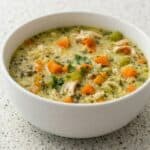 Bowl of creamy turkey and rice soup with carrots and herbs, a cozy leftover turkey soup recipe.