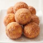 Cinnamon sugar banana donut holes stacked on a plate.
