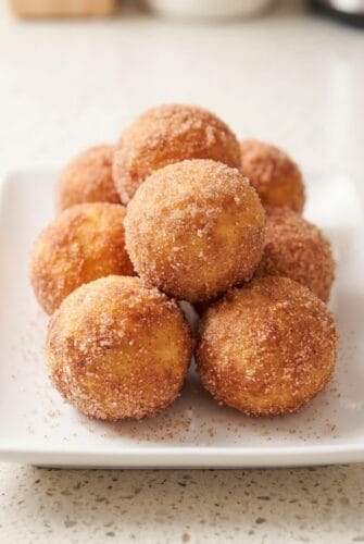 Air Fryer 2-Ingredient Banana Donut Holes {Sweet & Soft} Cinnamon sugar banana donut holes stacked on a plate.