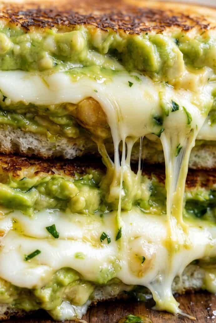 Close-up of avocado grilled cheese showing gooey melted cheese and creamy avocado between crispy bread.