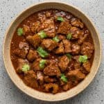 Tender beef vindaloo in a rich spiced curry sauce topped with fresh cilantro.