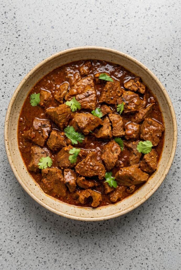 Tender beef vindaloo in a rich spiced curry sauce topped with fresh cilantro.