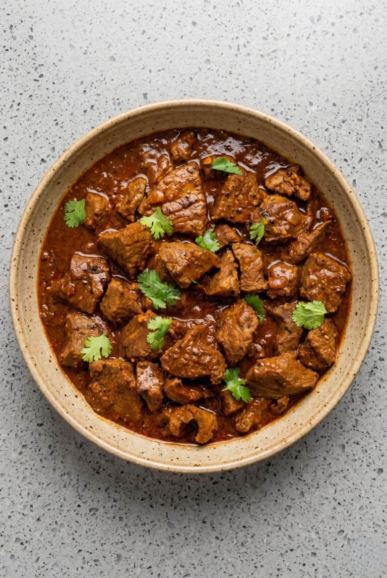 Tender beef vindaloo in a rich spiced curry sauce topped with fresh cilantro.