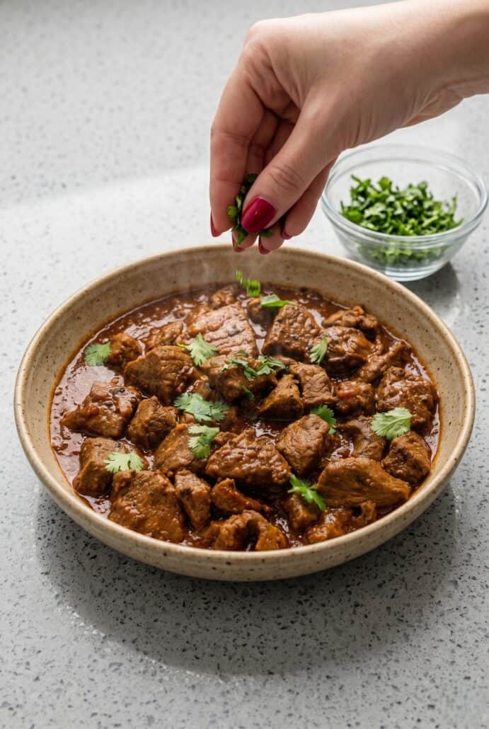 Fresh cilantro sprinkled over a bowl of homemade beef vindaloo curry.