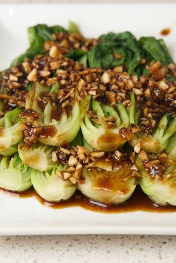 Close-up of tender bok choy topped with savory garlic soy sauce and minced garlic.