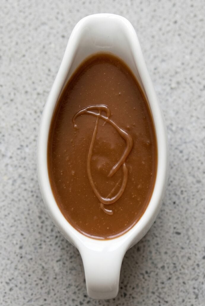 Homemade caramel sauce in a white serving dish, ready for drizzling over desserts.