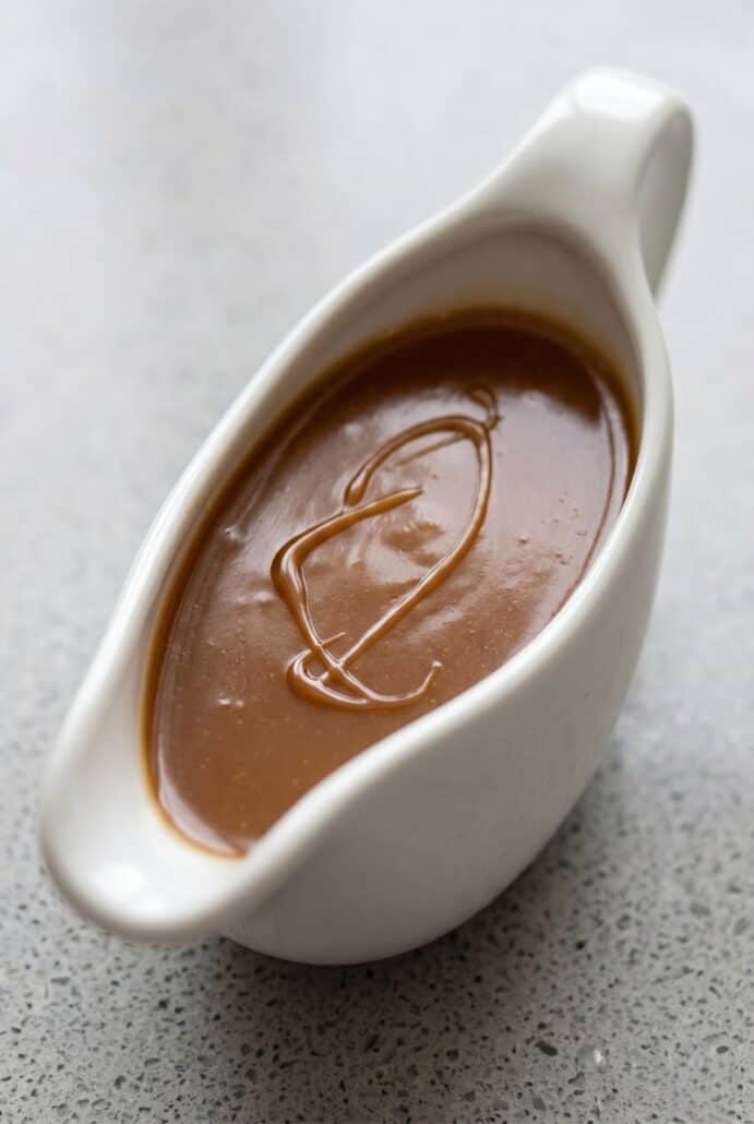 Creamy homemade caramel sauce in a white gravy boat, ready to drizzle over desserts.