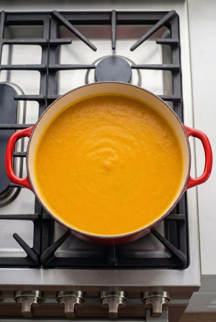 Creamy carrot soup blended smooth in a Dutch oven on the stovetop.