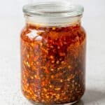 Homemade Chinese chili oil stored in a glass jar, ready to add spicy flavor to noodles, dumplings, and rice.