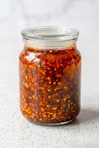 Homemade Chinese Chili Oil Recipe (Spicy, Flavorful & Addictive!) Homemade Chinese chili oil stored in a glass jar, ready to add spicy flavor to noodles, dumplings, and rice.