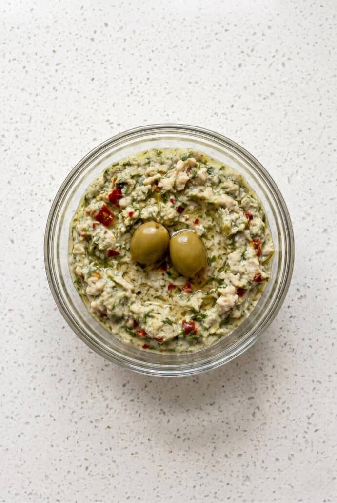 Creamy feta and green olive spread topped with whole olives, showcasing a chunky Mediterranean dip.