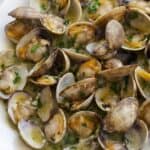 Close-up of garlic butter sauteed clams with parsley in a flavorful white wine sauce.