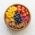 Healthy protein smoothie bowl topped with mango, strawberries, blueberries, and granola, served in a bowl.