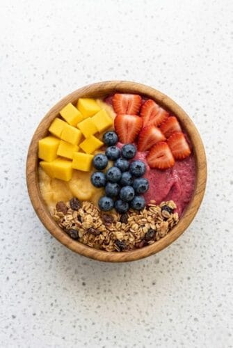 Protein Smoothie Bowl Recipe (Thick, Creamy & Ready in 5 Minutes!) Healthy protein smoothie bowl topped with mango, strawberries, blueberries, and granola, served in a bowl.