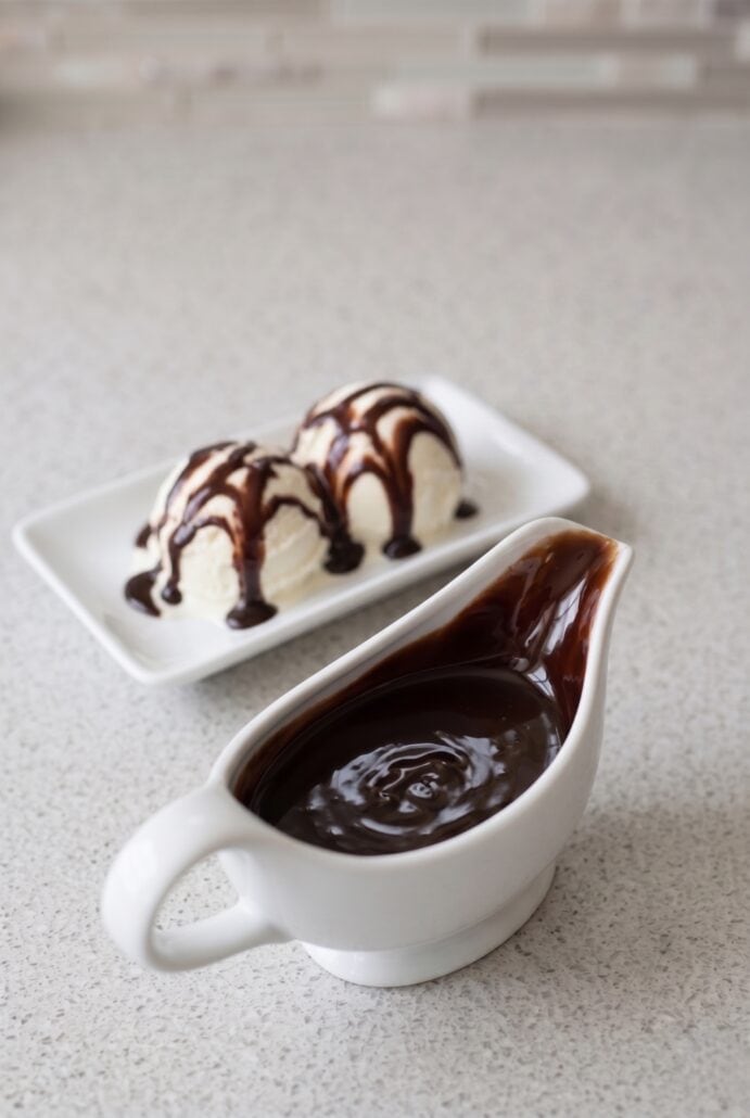 Vanilla ice cream drizzled with chocolate syrup served with extra sauce, perfect for a homemade chocolate dessert recipe.