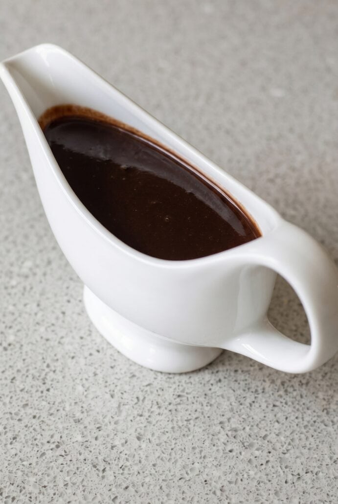 Close-up of rich homemade chocolate syrup in a white gravy boat, ready to serve as a dessert topping or chocolate milk mix.