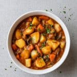 Bowl of Irish vegetarian stew with potatoes, carrots, peas, and fresh herbs in savory broth.
