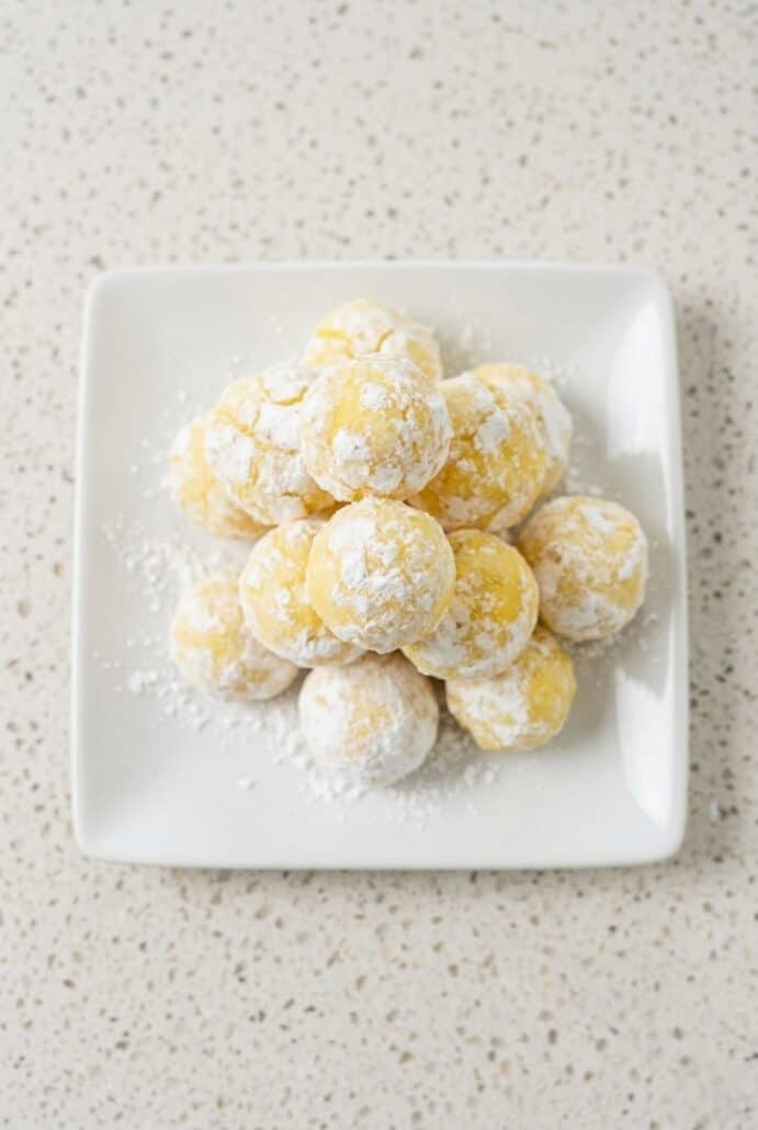 Powdered sugar-coated lemon white chocolate truffles arranged on a plate.