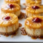 Mini pineapple upside-down cheesecakes with pineapple, cherry, and caramel topping.