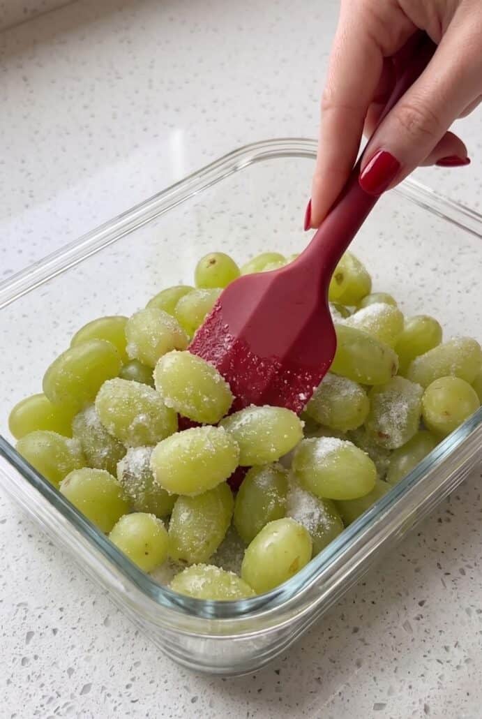 Grapes being coated with lime juice to make frozen Sour Patch Grapes.
