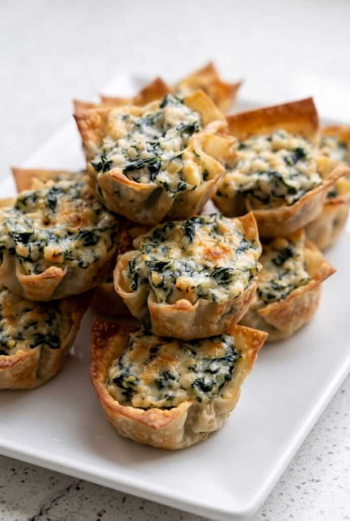 Close-up of crispy spinach artichoke wonton cups filled with creamy cheese appetizer filling.